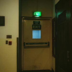 A dimly lit emergency exit door in a corridor with signage and safety indications.