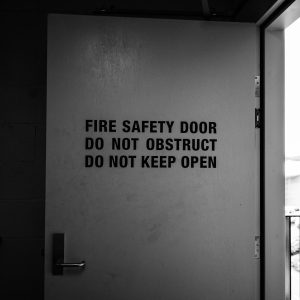 Black and white image of fire safety door with warning instructions.