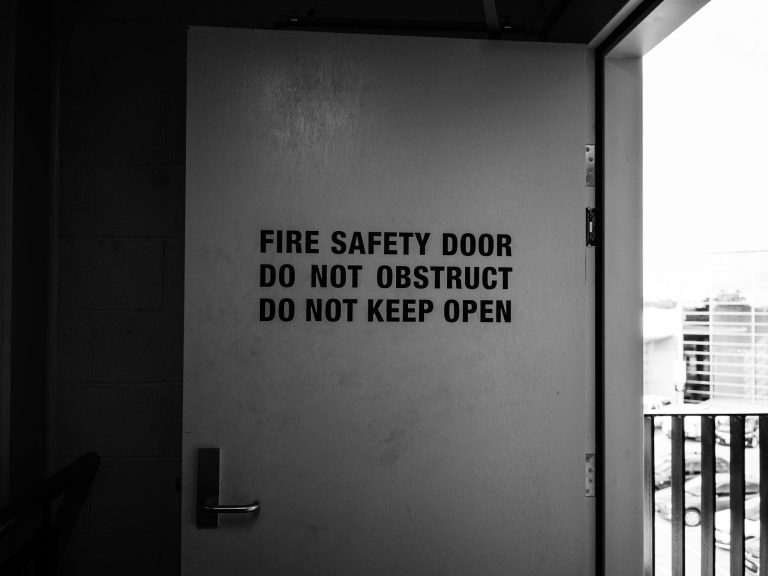 Black and white image of fire safety door with warning instructions.