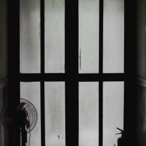 Dark silhouette image of a fire exit door with visible signage, creating a moody atmosphere.