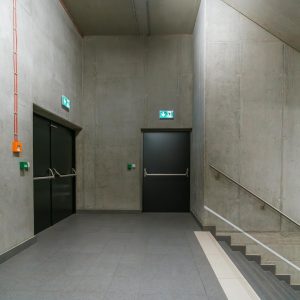 Modern indoor stairway with emergency exit doors in an industrial building.