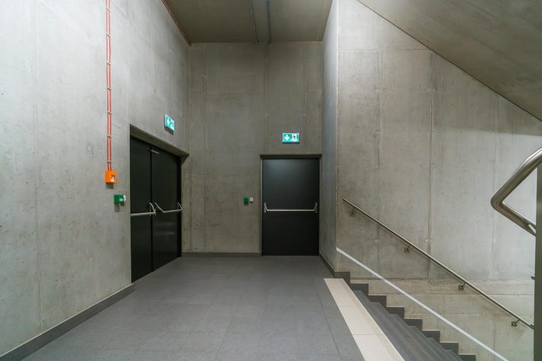 Modern indoor stairway with emergency exit doors in an industrial building.