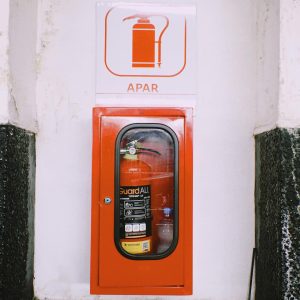 Wall-mounted red fire extinguisher with safety signage indoors.